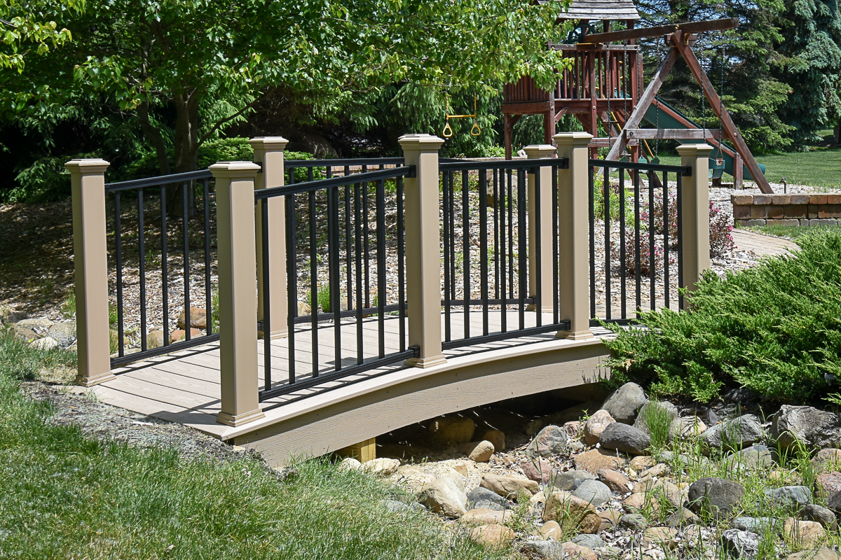 Custom Trex Transcend Rope Swing deck bridge with black Trex Signature railing in landscaped backyard