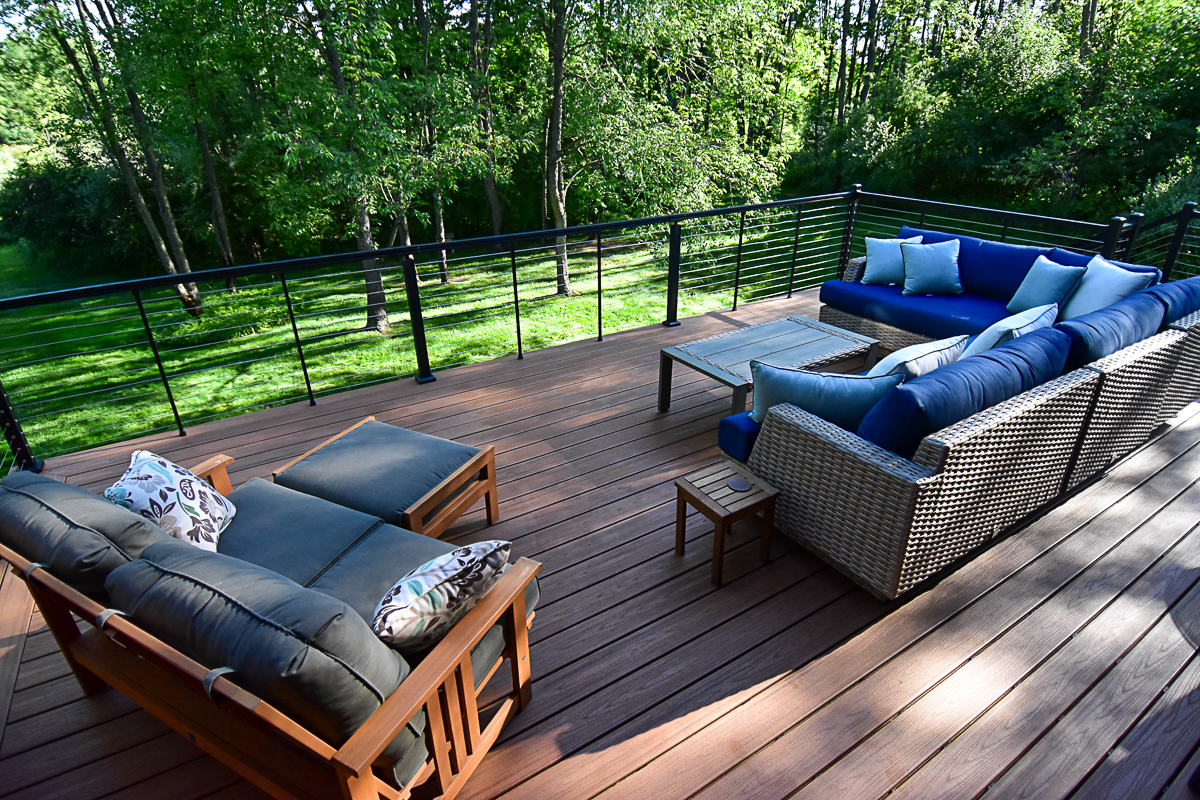 Trex Transcend Tiki Torch composite deck with black Key-Link horizontal cable railing in wooded backyard