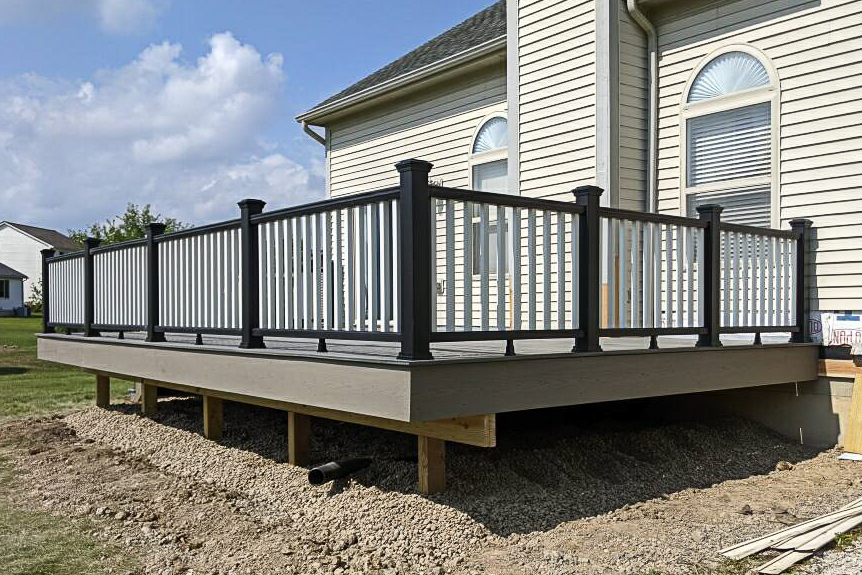 Trex Transcend Island Mist deck in Pittsfield Township with Gravel Path fascia, black Trex railing, and white balusters on a raised platform