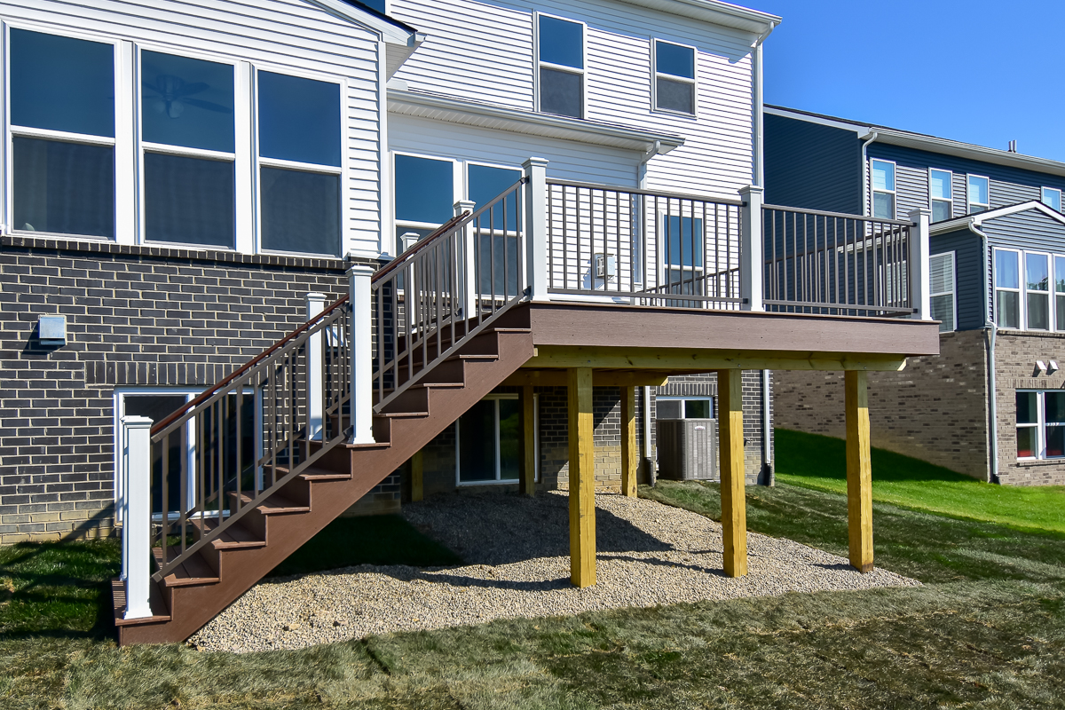 Trex composite deck with stairs in Saddle and Whisky Barrel tones, featuring white posts and bronze aluminum railing, built in Saline, Michigan