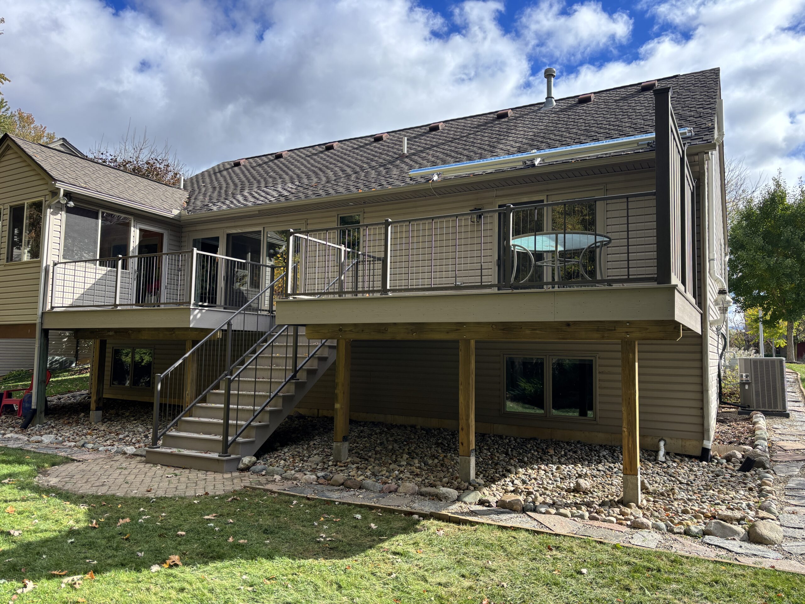 TimberTech composite deck in Slate Gray with aluminum cable railing and stair access, built in Saline, Michigan with elevated structure and privacy fence